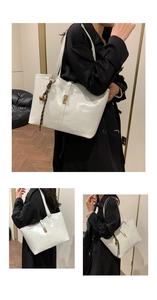 Close-up of white glossy tote bag with gold buckle and woven bell pendant detail
