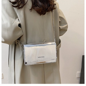 Detail of silver mirror finish small square bag with metal chain strap and logo
