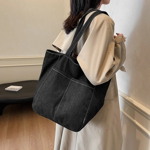 Large black denim tote bag with white contrast stitching and spacious front pockets