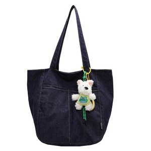 Dark blue denim tote bag with plush charm and contrast stitching on a white background