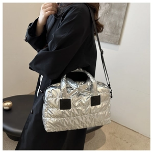 Detail einer silbernen gesteppten Daunentasche mit Metallic-Finish und breitem Schultergurt