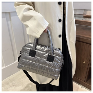 Detail der silbernen gesteppten Puffer-Tasche mit Metallic-Finish und schwarzen Griffen