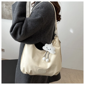 Detail of cream white half-moon hobo bag with a cute white plush cloud charm accessory