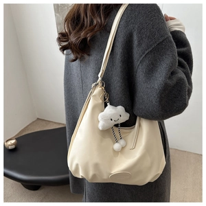 Detail of beige PU leather hobo bag with a soft cloud plush pendant and oval brand tag
