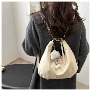 Detail of cream white leather hobo bag with soft pleats and cloud plush pendant