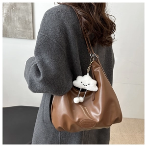 Brown leather hobo shoulder bag with a fluffy cloud charm shown on a model's back