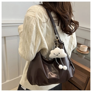 Detail of a large dark brown pleated hobo bag with a soft white cloud plush charm