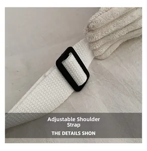 Detail of adjustable white woven shoulder strap with black buckle on corduroy tote bag