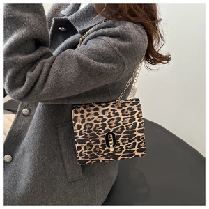 Close-up of leopard print crossbody bag with gold chain strap on grey wool coat