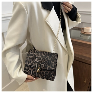 Close-up of leopard print crossbody bag with gold chain strap on a white blazer