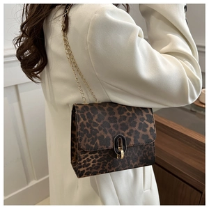 Detail of leopard print crossbody bag with gold chain strap on white blazer