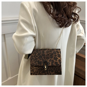 Detail of leopard print crossbody bag with gold metal chain strap on model outfit