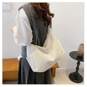 Detail of off-white corduroy tote bag showing ribbed texture and wide shoulder strap
