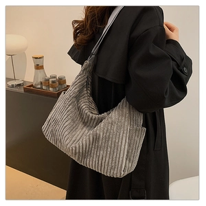 Close-up of grey corduroy tote bag texture worn with a black coat in a stylish setting