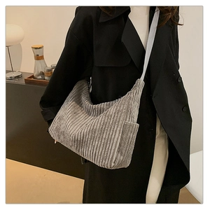 Detailed texture of a grey corduroy crossbody bag worn in a casual indoor setting