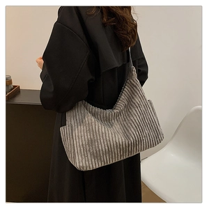 Side view of a large grey corduroy tote bag worn over the shoulder for a casual style