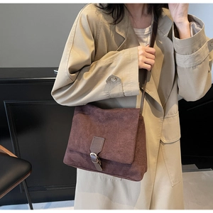 Dettaglio di una borsa a tracolla in pelle scamosciata marrone con texture opaca e fibbia retro