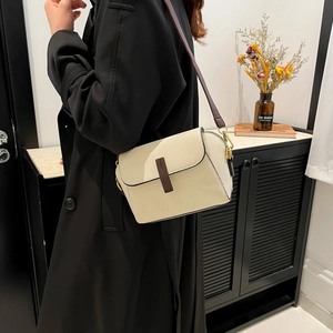 Retro cream beige crossbody bag with dark brown leather trim on black coat model