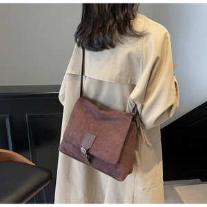 Dettaglio di una borsa a tracolla vintage marrone in pelle scamosciata con fibbia