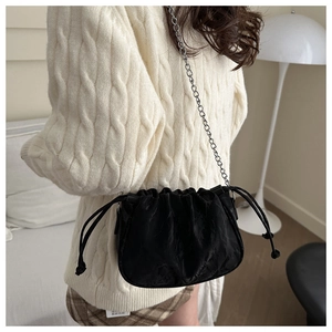 Detail of black pleated cloud bag with silver chain strap shown in a lifestyle setting
