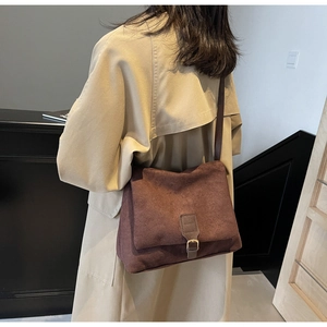 Dettaglio borsa tote vintage marrone opaca con fibbia in metallo indossata su trench