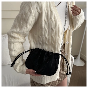 Close-up of black drawstring bucket bag with silver chain strap and ruched fabric texture
