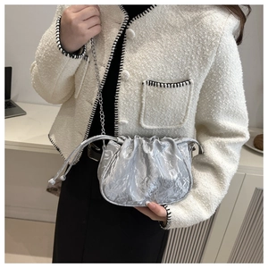 Close-up of metallic silver drawstring bucket bag with textured pleats and chain strap