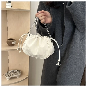 Detail of white drawstring cloud bucket bag with silver chain and soft leather texture