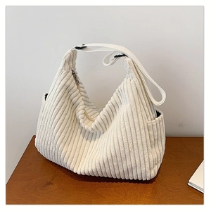 Detail of white corduroy shoulder bag showing side pocket and adjustable fabric strap