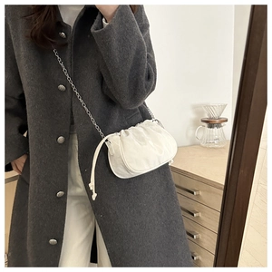 Detail of white pleated cloud bag with silver chain strap shown in a lifestyle mirror shot