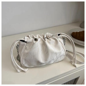 Detail of white pleated cloud bag showing drawstring closure and silver chain strap