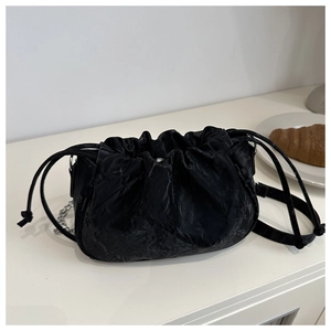 Detail of black pleated cloud bag with drawstring closure and silver chain strap