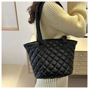 Detail of black quilted puffer tote bag showing glossy texture and large capacity space