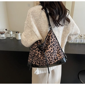 Detailed view of leopard print tote bag with black leather base and decorative bow
