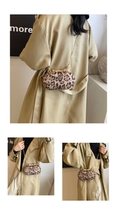 Detail van ovale tas met luipaardprint, gouden striksluiting en metalen ketting
