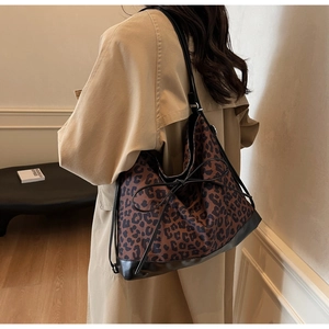 Leopard print tote bag with black bow detail worn over a stylish khaki trench coat