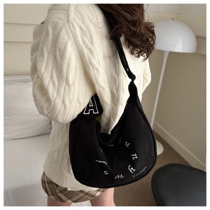 Close-up of black corduroy hobo bag with white letter embroidery and ribbed texture