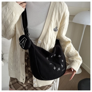 Détail du sac bandoulière en velours noir avec broderie et breloque ronde