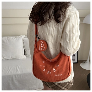 Detail of orange corduroy tote bag with embroidery and round coin purse attachment