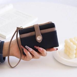 Detail of vintage bi-fold mini wallet with zipper pocket and wrist strap in black and coffee