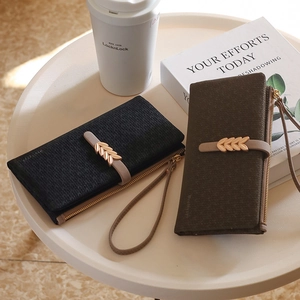 Detail of leaf-patterned long wallets in black and dark brown litchi leather