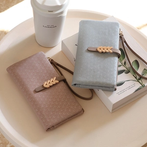 Close-up of premium leaf pattern leather wallets with golden tassels and wristlet straps