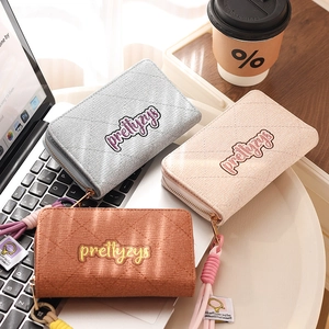 Detail of quilted corduroy wallets in grey, pink, and brown with woven tassel charms