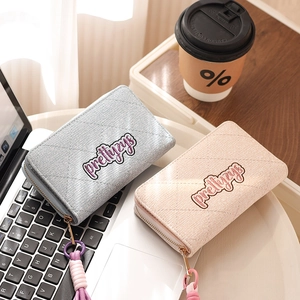 Detail of light blue and pink lattice quilted wallets with tassels on a laptop keyboard