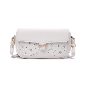 Detail of cream crossbody bag featuring leaf print pockets and gold leaf metal buckle