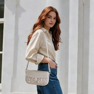 Detail of grey crossbody bag with floral pattern flap and metal buckle on casual model