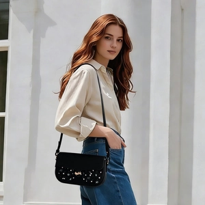 Close-up of a stylish black leather crossbody bag with starry sequin detailing and gold logo