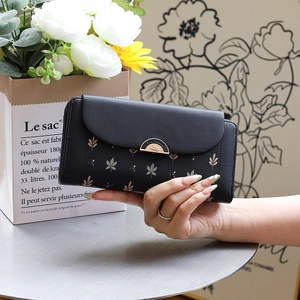 Short tri-fold wallet for women with leaf pattern and gold metal clasp in hand