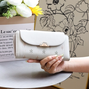 Close-up of small floral wallet with magnetic metal buckle held by hand in a lifestyle scene