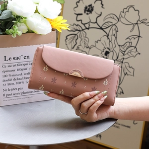 Close-up of pink tri-fold wallet featuring leaf print and a metallic semicircle buckle